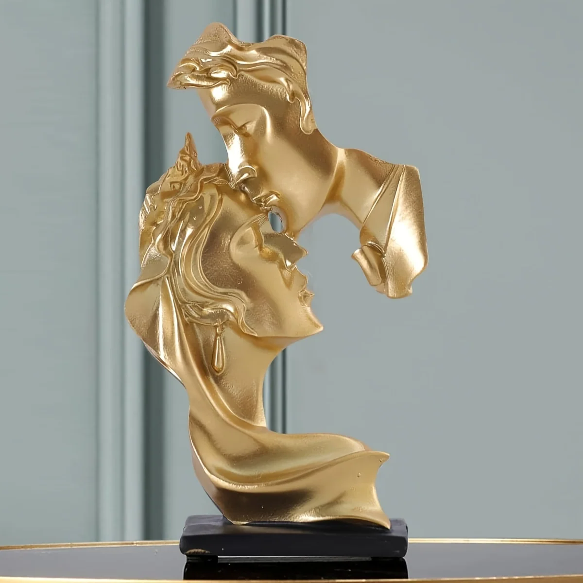 Golden-tone resin sculpture of a kissing couple with black base